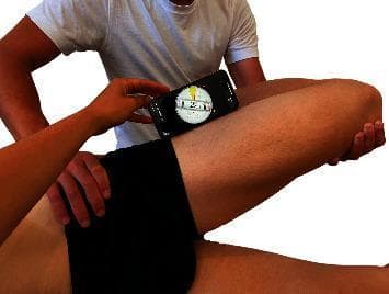 This clinical photograph demonstrates the objective measurement of the Ober test using a smartphone-based digital inclinometer. The patient is positioned in a side-lying posture. The examiner’s left hand is placed on the superolateral aspect of the patient's pelvis to provide stabilization and prevent compensatory pelvic tilt. The examiner’s right arm supports and cradles the patient's flexed knee (at approximately 90 degrees) while guiding the hip through abduction, extension, and into adduction. A mobile device running a clinometer application is positioned on the lateral mid-thigh, aligned between the anterior superior iliac spine (ASIS) and the lateral femoral condyle. The digital interface displays a measurement of 21 degrees, indicating the hip range of motion or degree of adduction at the point of tissue resistance. This procedure is utilized in physical therapy and orthopedics to assess the flexibility or tightness of the iliotibial band (ITB) and tensor fasciae latae (TFL) complex.