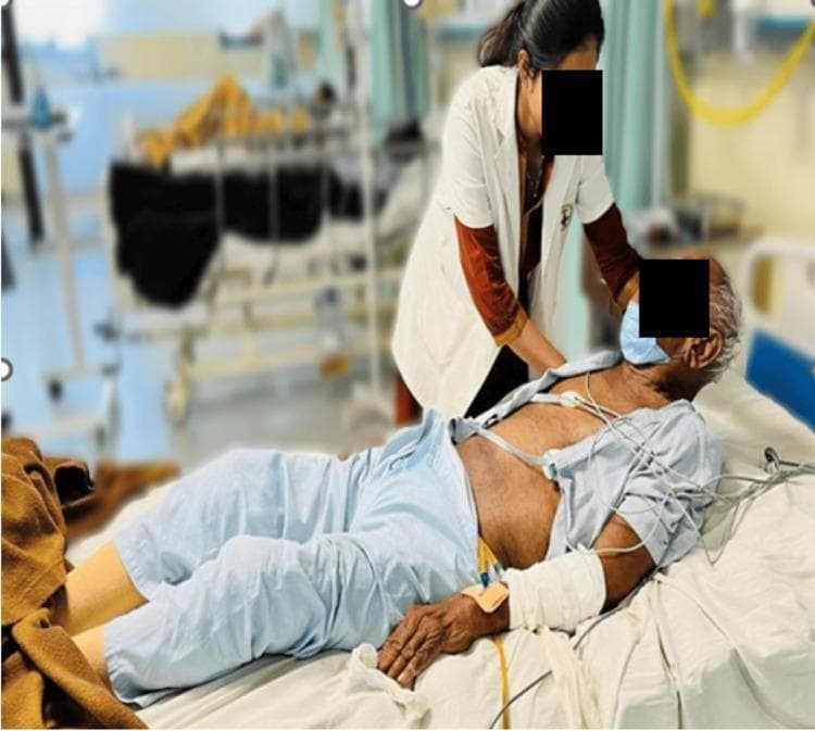 Clinical photograph demonstrating the elicitation of Brudzinski's sign in a supine patient, indicative of meningeal irritation or neck rigidity. A healthcare professional is shown performing passive flexion of the patient's neck. The positive sign is evidenced by the involuntary flexion of the patient's hips and knees in response to the neck movement. The patient is situated in a hospital bed with visible monitoring equipment, including ECG leads on the chest and an intravenous (IV) line in the left arm. This clinical maneuver is essential in the neurological physical examination for suspected meningitis or tuberculous meningitis (TBM). The photograph captures the classic postural response associated with meningismus, serving as an educational resource for medical students and practitioners on neurological assessment techniques.