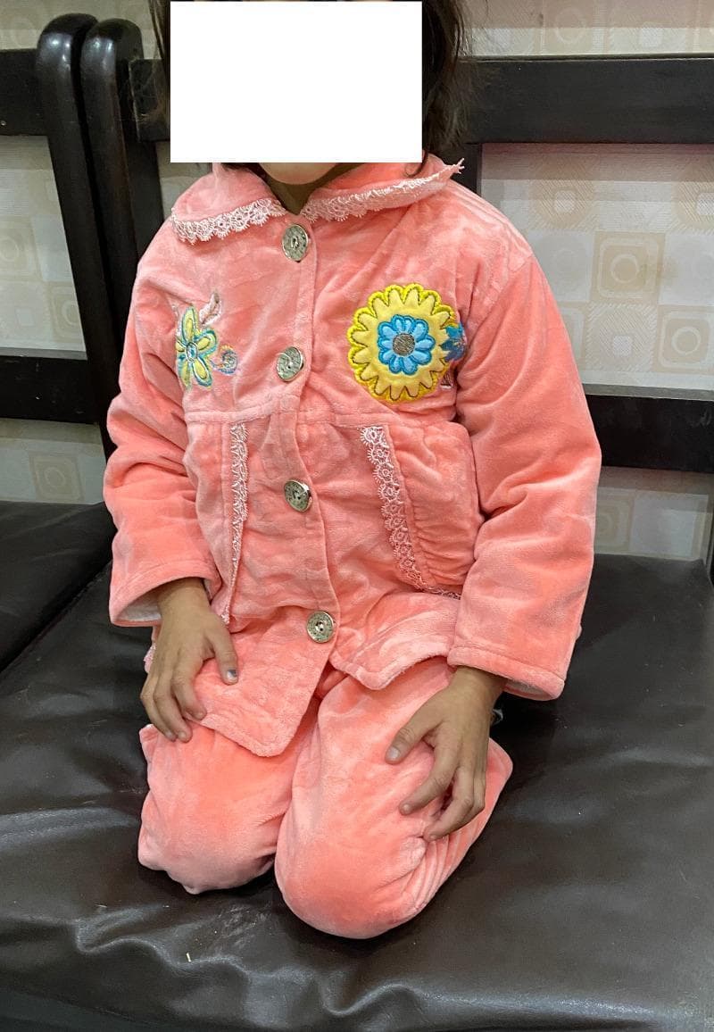 Clinical photograph of a pediatric patient demonstrating postoperative lower limb functional mobility following a Salter's innominate osteotomy (SIO) for developmental dysplasia of the hip (DDH). The subject is shown in a seated kneeling position, often used for clinical assessment in certain cultures. The image illustrates the 'tashahhud I' position, which is a component of the Bhatti Functional Scoring System (BFSS) used to evaluate clinical outcomes after pelvic osteotomies. Key visible features include the ability to achieve significant knee flexion and hip stability necessary for this specific kneeling posture. This clinical documentation is used to assess the range of motion, hip joint stability, and the success of surgical reconstruction in restoring functional activities of daily living in a pediatric orthopedic context. The patient's symmetrical posture and bilateral limb alignment are indicative of a successful surgical outcome and effective postoperative rehabilitation.