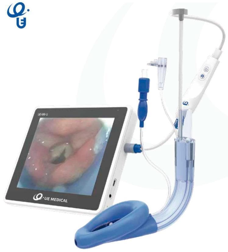 This clinical photograph displays the SaCoVLM video laryngeal mask airway (LMA) system, a specialized supraglottic airway device designed for visualization during airway management. The assembly consists of a curved, semi-transparent breathing tube terminating in a blue, inflatable anatomical mask cuff. Integrated into the device is a video stylus system connected to a handheld control unit with power and capture buttons. Multiple access ports are visible along the tube, including a central channel for gas exchange or endotracheal tube (ETT) insertion, a gastric drainage port, and ports for pressure monitoring and CPAP ventilation. The handheld unit is tethered via a blue connector to a 7-inch portable monitor. The monitor screen displays a high-definition endoscopic view of the glottis, showing the vocal cords and epiglottis, which allows for real-time visual confirmation of device placement and facilitates rescue intubation. This medical technology is utilized by anesthesiologists and emergency physicians to secure the human airway while providing direct visualization of the larynx.