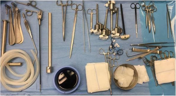 This intraoperative clinical photograph displays a comprehensive instrumentation set organized on a sterile blue drape, prepared for a thyroidectomy or a similar head and neck surgical procedure. The set combines traditional open surgical tools with specialized endoscopic equipment. Key categories of instruments visible include: (1) Dissection and Cutting: Metzenbaum scissors (short and long), a scalpel handle, and monopolar electrocautery with a long tip extension. (2) Grasping and Clamping: Various forceps including DeBakey atraumatic forceps (short and long), Klemmer tissue forceps, and Johann forceps. (3) Retraction: Farabeuf and Langenbeck wound retractors alongside a specialized modified thyroidectomy retractor (Modena retractor) designed for specific working space maintenance. (4) Minimally Invasive/Endoscopic Tools: A 30° endoscopic camera, multiple trocars, a vessel sealing device for hemostasis, and an endoscopic suction/irrigation assembly with flexible tubing. (5) Miscellaneous: Sterile gauze pads and a basin containing surgical solution. This image serves as an educational reference for perioperative nursing and surgical preparation for combined open and endoscopic neck surgery.