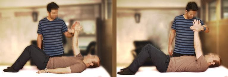 This clinical photograph consists of two panels demonstrating a therapeutic shoulder exercise, specifically manual resistance during shoulder abduction. The patient is positioned supine on a flat surface with knees flexed and feet flat. In the left panel, the patient has one arm raised vertically (flexed to 90 degrees at the shoulder) while an assistant stands beside him, preparing to apply medial force. In the right panel, the assistant provides manual resistance toward the patient’s midline (adduction force), which the patient counteracts by pushing outward against the assistant’s hand (abduction). This procedure represents a neuromuscular re-education or strengthening exercise for the rotator cuff and deltoid muscles. The setting is a rehabilitation or clinical environment. Educational focus is on manual resistive training (MRT) techniques used in physical therapy for upper extremity stabilization and strength progression.